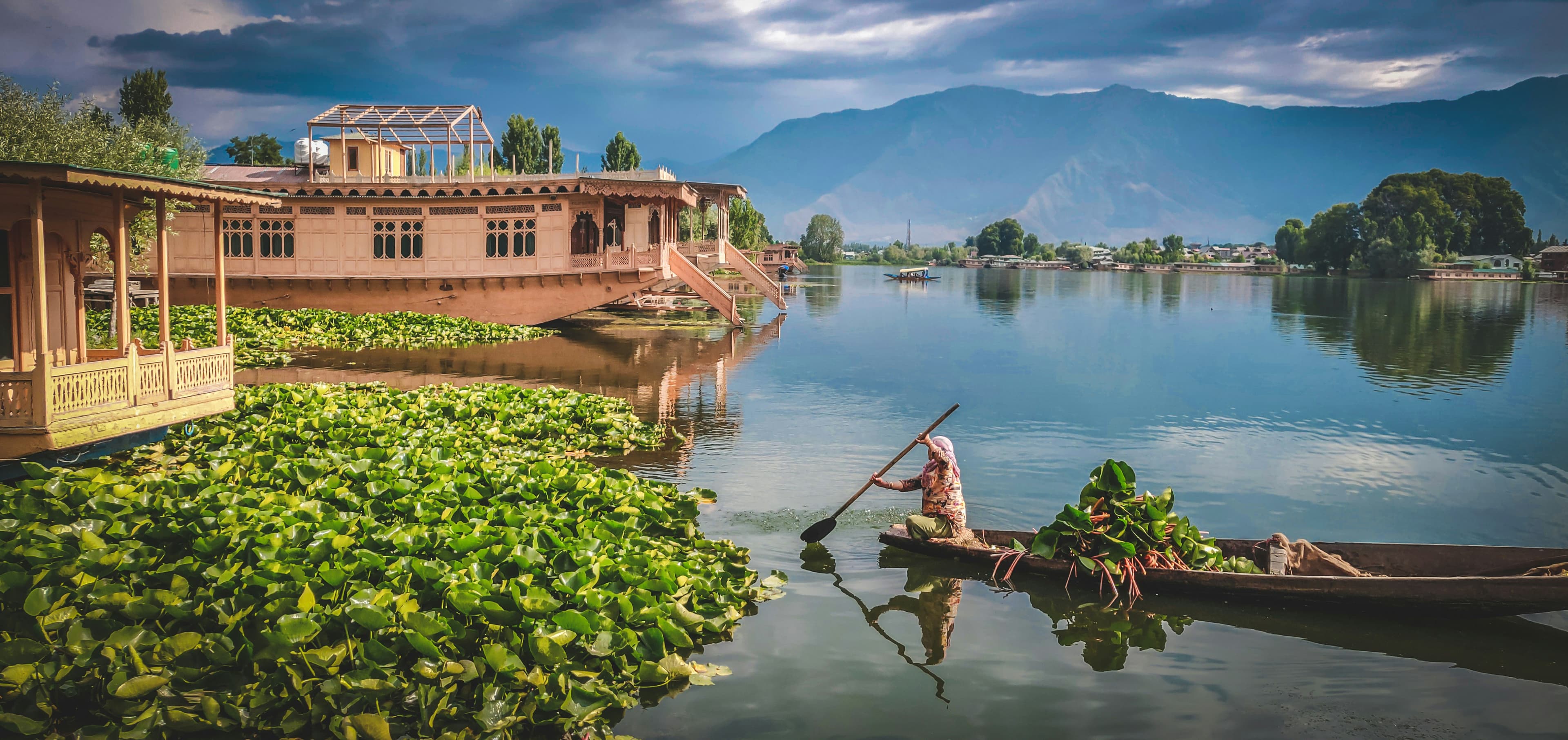 Shikara boat on Dal Lake with houseboats and mountains, Srinagar